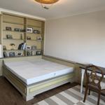 Bedroom with bed, desk, and wall unit with picture frames.