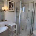 Bathroom with shower, sink, and toilet. Wall picture and mirror are visible.