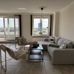 Living room with sofa, two chairs, and balcony view