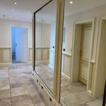 Hallway with mirrored closet, light walls, and tiled floor.
