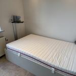 A bed with mattress and pillow in a room with window and radiator.