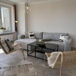 Living room with gray sofa, two rattan chairs, and large window.