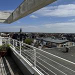 Terrace with view of town and church under blue sky.