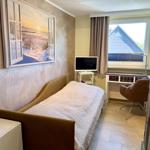 Ein Schlafzimmer mit Bett, Schreibtisch, Fernseher und Fenster.