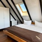 Schlafzimmer mit Dachschrägen, Dachfenster und Holzboden.