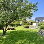 Garten mit Baum, Grill und Sitzbereich vor einem Haus.