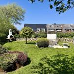 Garten mit Grill, Sitzgruppe und Rasenfläche. Im Hintergrund sind Häuser zu sehen.