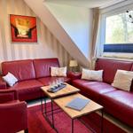 Zwei rote Sofas und ein Tisch mit Glasgefäßen stehen im Wohnzimmer.