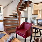 Rote Ledersessel, Holztisch, Treppe und Küchenbereich im Wohnraum.