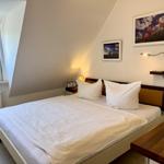 Schlafzimmer mit Doppelbett, Fenster und Wandbildern.