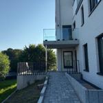 Haus mit Balkon, gepflasterter Weg und grüner Umgebung.