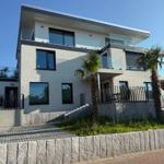 Moderne Villa mit Balkon und Palmen im Außenbereich.