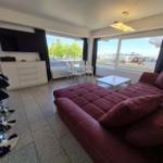Wohnzimmer mit rotem Sofa, TV und großem Fensterblick.