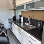 Moderne Küche mit Arbeitsplatte, Spüle, Kühlschrank und Kochfeld.