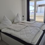 Schlafzimmer mit Doppelbett, zwei Nachttischen und Balkonansicht.