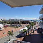 Blick auf belebten Strandpromenade mit Geschäften und Fahrrädern.