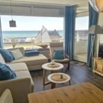 Wohnzimmer mit Blick aufs Meer, Sofa, Sessel und TV.