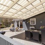 Patio with seating, grill, and loungers under roof. View into garden with slide.