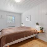 Bedroom with bed, window, and wooden floor.