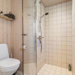 Bathroom with shower, toilet, and wooden wall cladding.