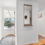 House with entryway, mirror, and view of terrace with lounge chairs.