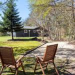 Two wooden chairs sit in the garden facing a house with lawn and trees.