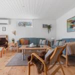A living room with wooden floor, blue sofas, and wooden furniture. A painting hangs on the wall.