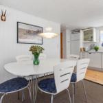 Dining area with white table and chairs, kitchenette and wall decor