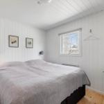 Bedroom with bed, window, and green dresser. Walls and ceiling are white paneled.