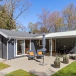 A gray vacation home with terrace, garden, and grill area. Wooden windows and seating are visible.