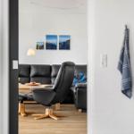 A living room with a black sofa and a chair. Pictures hang on the wall.