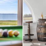 View of lake and green meadows. Wooden barrel with wine and two stools.