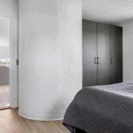 Bedroom with bed, wardrobe, and pillar. Passage to shower with tiled floor.