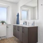 Bathroom with sink, mirror, toilet, and window.