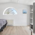 Room with double bed, ladder, and bunk bed. Arched window and wooden floor.