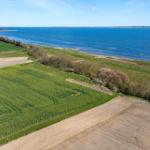 Extensive landscape with fields and coast. Blue sea and green meadows.