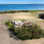 House with surrounding fields and view of a lake.