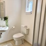 Badezimmer mit Waschbecken, Toilette und Dusche. Fenster mit Handtuch.