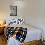 Ein Schlafzimmer mit Bett, Kissen, Tischlampe und Wandbild.