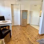 Essbereich mit Tisch, zwei Stühlen und Holzboden. Hintergrund: Tür und Kleiderschrank.