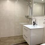 Moderne Dusche mit Glaswand, Waschbecken und Spiegel an der Wand.