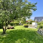 Garten mit Baum, Grill und Sitzgruppe vor einem Haus.