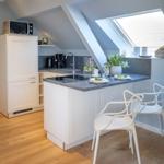 Küche mit Essbereich, Dachschrägen und Dachfenster. Weiße Möbel und Holzboden.