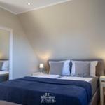 Schlafzimmer mit Doppelbett, zwei Nachttischen und Spiegel an der Wand.