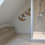Dusche mit Glaswand, Wanddekoration aus Holzanker und Korb auf dem Boden