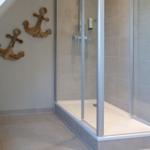 Dusche mit Glaswand und hölzernen Ankerdekoration an der Wand.