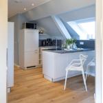 Küche mit weißer Arbeitsplatte, Holzboden und Dachschrägen.