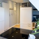 Küche mit Induktionskochfeld, Mikrowelle und weißen Schränken unter schräger Decke.