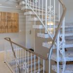 Haus mit Treppe und Holzschild mit Schriftzug. Treppenstufen aus Stein.