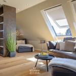 Wohnbereich mit Sofa, Sitzbank und Dachfenstern. Holzboden und eingebaute Regale.